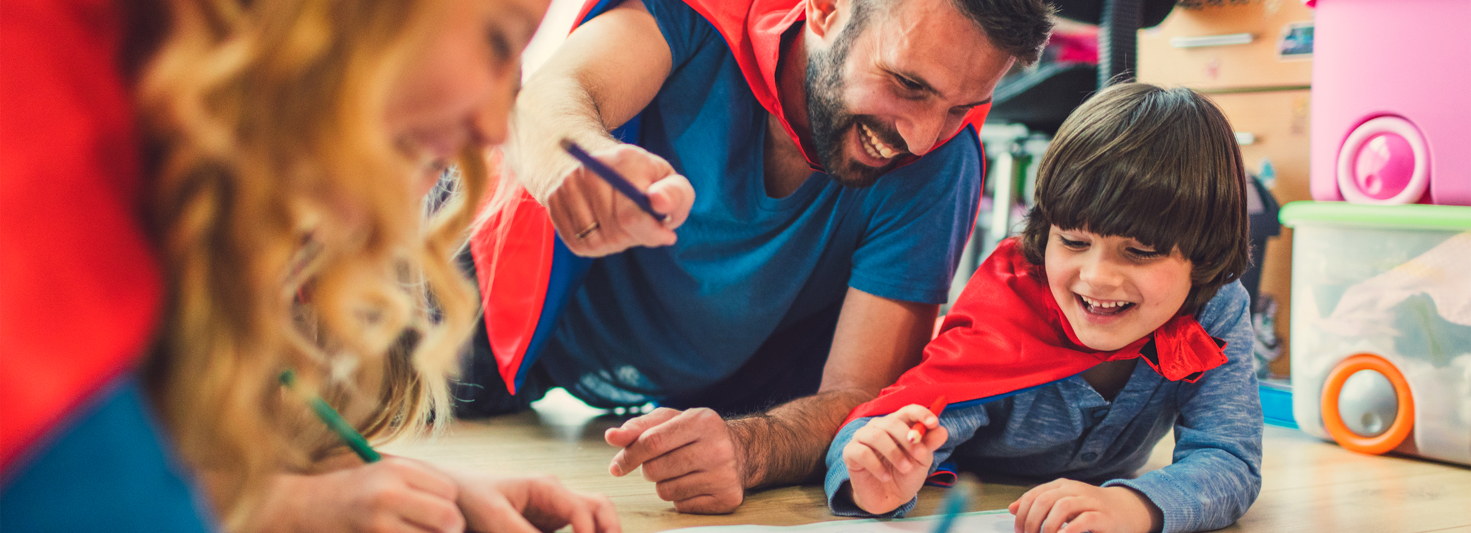 Parents and children playing together wearing superhero capes